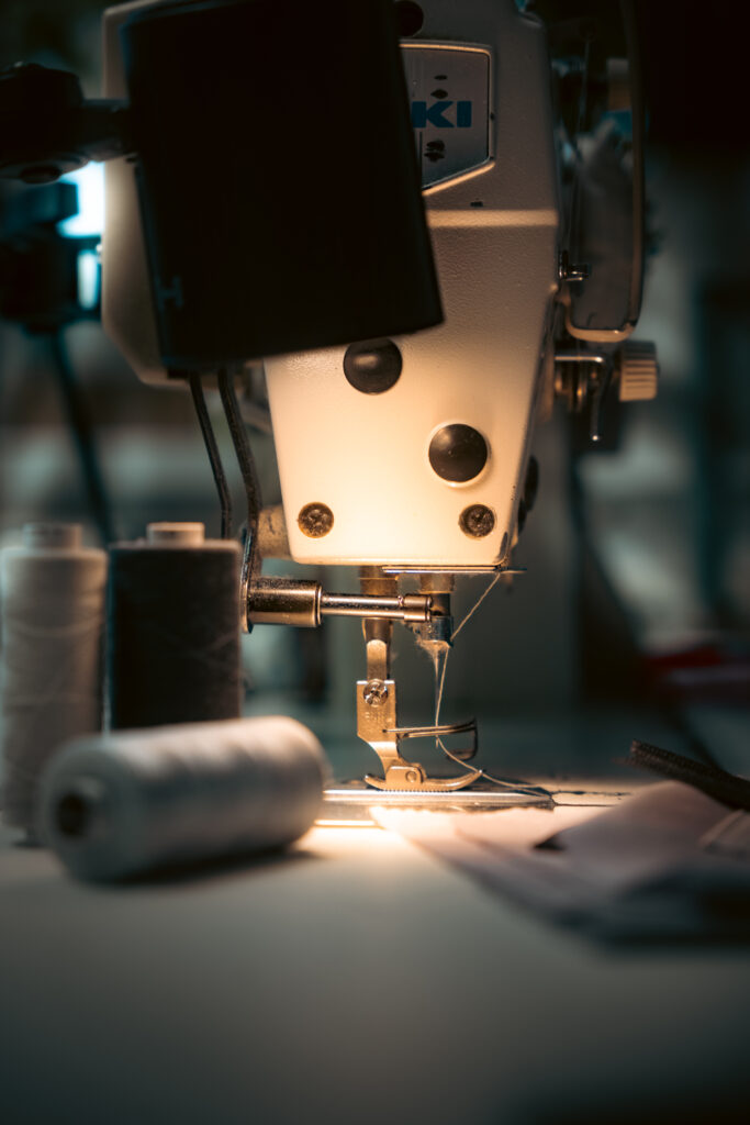 Nahaufnahme einer Nähmaschine mit Garnrollen im Atelier – fotografiert für Textilio durch SceneSation Dresden