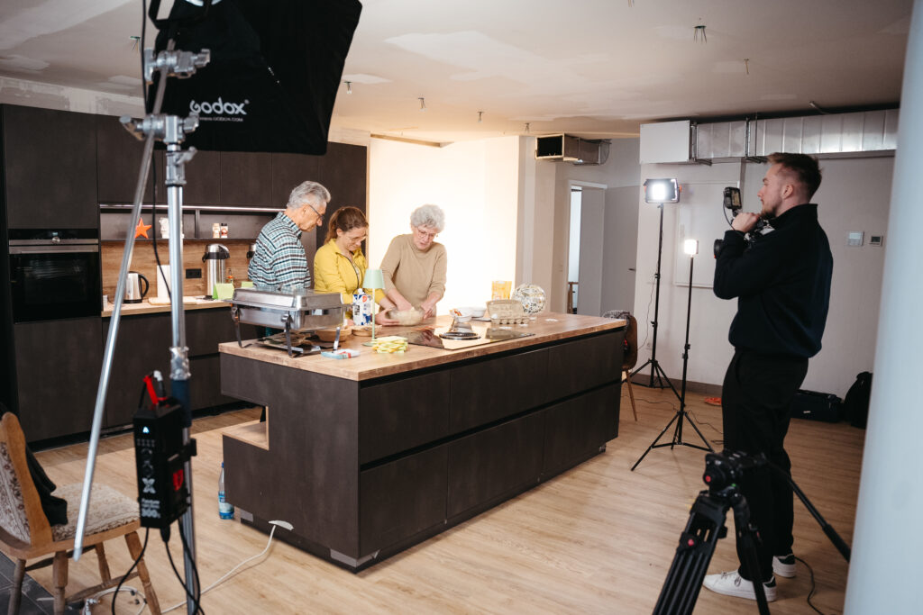 Leandro Matthiessen filmt drei Senioren beim gemeinsamen Backen in einer modernen Küche