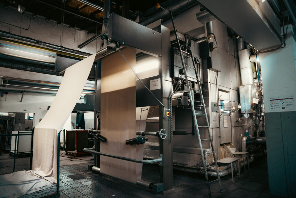 Industriemaschine verarbeitet große Stoffbahnen in einer Textilfabrik – Szene aus der Produktion von Textilio
