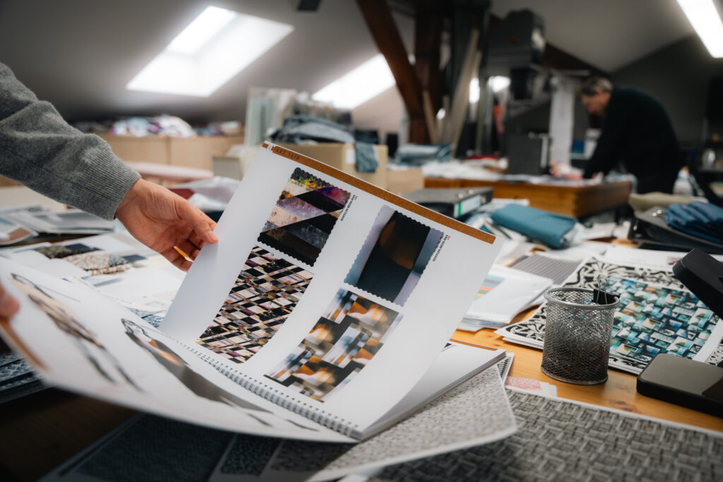 Person blättert durch Musterbuch mit Textildesigns – Szene aus der Imagekampagne für Textilio von SceneSation